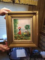 Frontal image of the framed enamel on copper artwork depicting a woman with red umbrella and two seated figures in a garden scene.