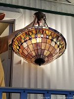 Front side view of the Tiffany style faux stained glass pendant light being held up to show size and pattern.