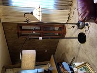 Both floor lamps shown together in a room with carpet and wood paneling, showcasing size and style difference.