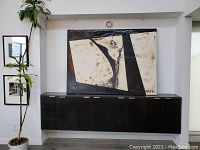 Front view of large abstract painting displayed above a cabinet, showing size and wall hanging context.