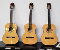 Three Fujiyama 3/4 size classical guitars side by side on a black cabinet against a white wall