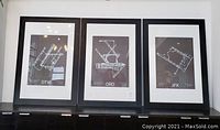 Front view of three black-framed airport runway prints labeled DTW, ORD, and JFK, displayed on a cabinet.
