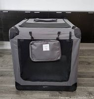 Front view of gray Amazon Basics dog crate with black mesh door panel and attached small pouch labeled 14.