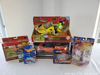 Group photo showing all toys including Bugatti Veyron RC car, Dinotrux toy, Hot Wheels cars, Zhu Zhu Pets, and DragonBall Z figure in original packaging.