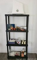 Full view of all items displayed on a 4-tier black plastic shelving unit showing Honeywell humidifier on top shelf, various candles and tea lights on middle shelves, and candle wax, oil, and sprays on lower shelves.