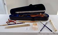 Violin in blue hard case with assorted drumsticks, snare brushes, recorders, and bell shakers laid out in front.