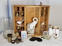Front view of the handmade wooden display cabinet with glass, showing various ceramic and glass decor items arranged inside and around it.