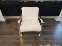 Front view of the white leather Mobital accent chair with chrome frame on wooden floor.
