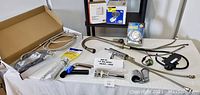 Overview of plumbing hoses, drain assemblies, faucets, thermostat and other parts in box
