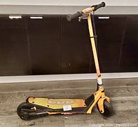 Photo of entire scooter side view showing orange and black frame with EVE branding on deck.