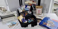 Full lot on table showing Cricut machine, storage bins, stamps, scissors, scrapbooks and craft bottles