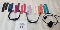 Overview of the two Fitbit Alta trackers with various extra colored wristbands laid out and two charging cables.