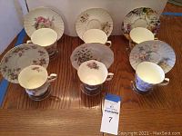Overall view of 6 bone china teacup and saucer sets arranged on wood table, including cup, saucer and stand for each set