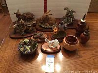 Overview of all figurines, decor, and wooden bowls on wooden table, labeled lot 39