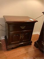 First nightstand front view showing top drawer and cabinet doors with brass handles