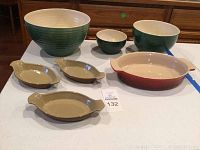 Full set showing Le Creuset baking dish, three brown oval dishes, and three nesting bowls arranged on white table.