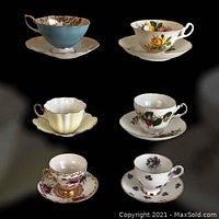 Set of 6 assorted English cups and saucers displayed on black background showing different designs and floral motifs.