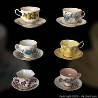 Photo showing all six assorted cups and saucers arranged in two columns on black background.