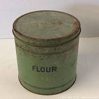 Front view of vintage flour tin with visible text and paint wear.