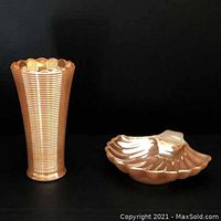Photo showing side-by-side view of the ribbed vase and shell dessert dish with peach lustre finish against a black background.