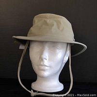 Front view of beige Tilley Airflow Hat on styrofoam head, showing adjustable chin strap and ventilation panel on crown.