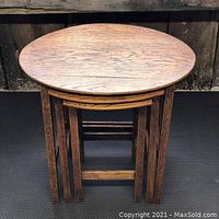Top view of stacked nesting tables showing oval largest table on top and two smaller square curved edge tables nested underneath.