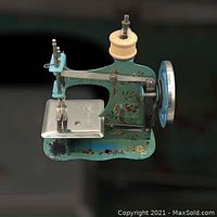 Top and side view of the small vintage child's sewing machine showing painted teal metal body with floral and bird designs, wooden spool pin, and metal needle plate.