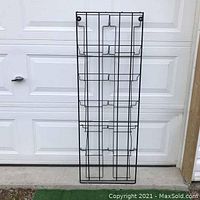 Front view of black metal wire retail display rack showing full height and wire compartments.