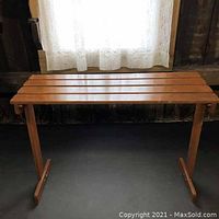 Wooden server or plant table with slatted top, visible in front view showing length and leg structure.