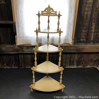 Front view of the wooden what-not stand showing five triangular corner shelves and turned spindle supports.