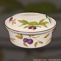 White porcelain round casserole dish with lid featuring painted fruit designs including plums and chestnuts with gold trim and handles.