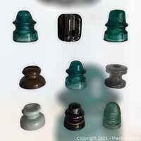 Top-view photo of all 9 porcelain and glass insulators laid out on a white surface in three rows.