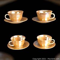 Set of four Fire-King lustre cups and saucers photographed on black background showing overall condition and lustre glaze.