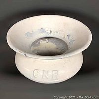 Top angle view of white painted metal spittoon with CNR embossed on side, showing paint chipping inside and outside.
