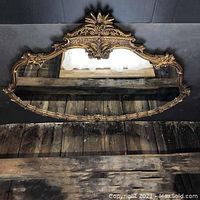 Front view of the large ornate decorative mirror showing intricate gold-toned floral frame and clear mirror glass.