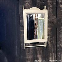 Front view of the vintage wooden medicine cabinet showing mirrored door and towel bar.
