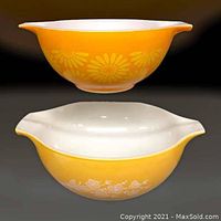 Photo showing both vintage Pyrex Cinderella mixing bowls stacked, showing yellow exteriors with Butterfly Gold and Daisy white floral motifs.