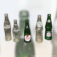 Front view of all five vintage soda bottles including two Coca-Cola, one Diamond Beverages, and two Canada Dry bottles.