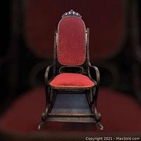Front view of vintage bentwood rocking chair showcasing the red upholstered high back and seat with carved wooden crest.