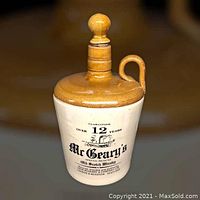 Front view of ceramic whiskey jug showing label and stopper.