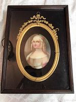 Frontal view of the oval porcelain portrait housed in a wooden frame with gold decorative oval surround.