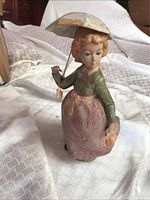 Full view of the Nadal girl figurine holding an umbrella, standing on a soft white textured surface.