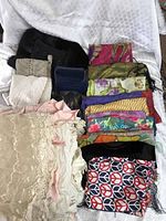 Image showing assorted scarves in various colors and patterns along with cream white christening gowns with lace and pleating.