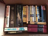 Books arranged upright showing titles such as The Norton Shakespeare, Tolkien's 'The Silmarillion', Heinlein's 'Stranger in a Strange Land', Dan Brown's 'Origin' and multiple classic novels with dust jackets.