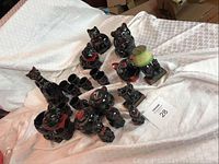 Overall view of black glazed ceramic cat vessels and figurines on white drape