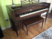 Full side view of the Acrosonic upright piano with matching bench, showing the mahogany finish and piano's size relative to the room.