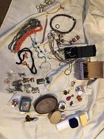 Photo showing laid out costume jewelry including necklaces, earrings, bracelets, some boxed pieces, and small trinket containers, with visible Alex and Ani items.