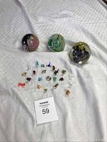 Photo showing the full set of 21 miniature blown glass animal figurines arranged around a nickel coin for size reference, with 3 spherical blown glass paperweights behind.