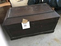 Photo of large dark wooden chest with latch on concrete floor