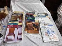 Photo showing the spread of 33 Fine Woodworking magazines and additional Woodsmith and Woodcraft magazines on display surface